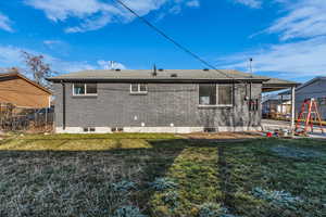Back of property with a yard, brick siding, a shingled roof, and a playground