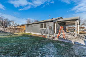 Rear view of property with brick siding, roof with shingles, and an attached carport