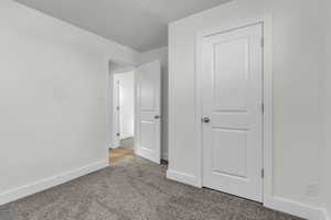 Unfurnished bedroom with carpet flooring and baseboards