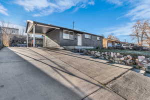 View of front of house with an attached carport, concrete driveway, and brick siding