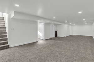 Finished basement with carpet flooring, stairway, and recessed lighting