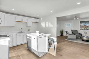 Kitchen with white cabinets, a center island, recessed lighting, and light wood finished floors