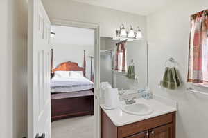 Ensuite bathroom featuring vanity, light colored carpet, and a shower stall