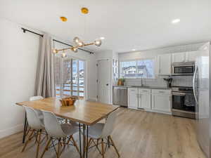 Dining room with light wood finished floors, recessed lighting, and a chandelier