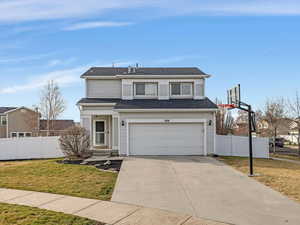 Traditional-style home featuring concrete driveway, a garage, and roof with shingles
