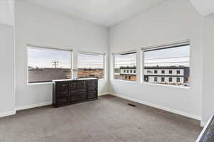 Master bedroom with light colored carpet and a towering ceiling