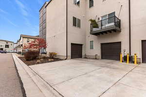 View of property exterior featuring a garage, a balcony, driveway, and stucco siding