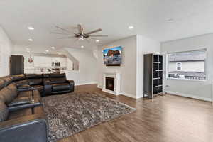 Living area with a fireplace, dark wood-type flooring, ceiling fan, and recessed lighting