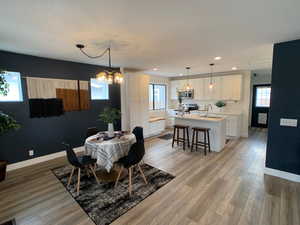 Dining room with healthy amount of natural light, light wood-type flooring, recessed lighting, and a chandelier