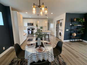 Dining room featuring stacked washer / drying machine, light wood-style floors, a chandelier, and recessed lighting