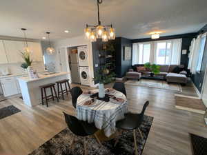 Dining room with stacked washer and clothes dryer, light wood-style floors, a chandelier, and recessed lighting