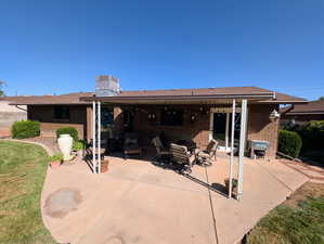 Rear view of property with brick siding, a patio area, a chimney, and a lawn