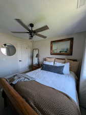 Bedroom with a textured ceiling, a ceiling fan, and carpet floors