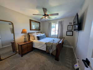 Carpeted bedroom with ceiling fan and baseboards
