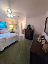 Carpeted bedroom with a textured ceiling, a ceiling fan, and ensuite bathroom