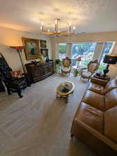 Carpeted living area featuring a textured ceiling and a chandelier