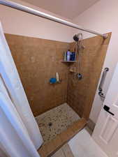 Bathroom featuring a shower stall, pet washing area, and tile patterned flooring