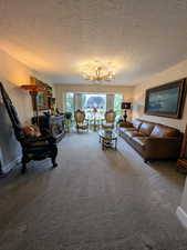 Living area featuring plenty of natural light, a textured ceiling, a chandelier, and carpet