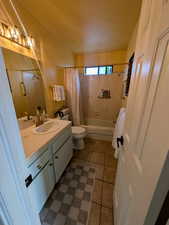 Full bathroom featuring vanity, shower / tub combo, and dark tile patterned flooring