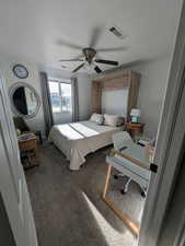 Bedroom with carpet floors, an office area, and a ceiling fan