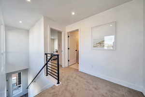 Hall featuring an upstairs landing, carpet floors, and recessed lighting