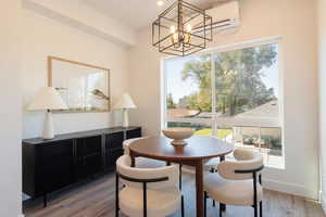 Dining space featuring light wood finished floors, a chandelier, and an AC wall unit