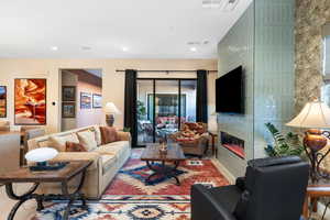 Living area with a glass covered fireplace, recessed lighting, and wood finished floors