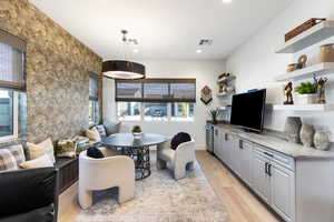 Living room with light wood finished floors, wallpapered walls, an accent wall, and recessed lighting