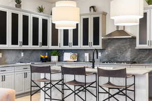 Kitchen featuring light stone countertops, backsplash, and glass insert cabinets