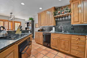 Kitchen with dark stone countertops, black appliances, a textured ceiling, brown cabinets, and recessed lighting