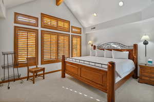 Bedroom featuring beam ceiling, light carpet, and high vaulted ceiling