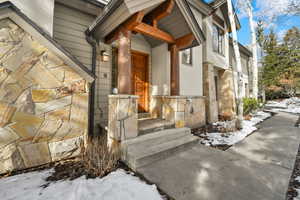 Snow covered property entrance with stone siding