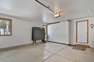 Garage featuring baseboards and a garage door opener