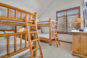 Bedroom featuring light colored carpet and vaulted ceiling
