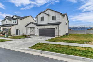 View of front facade with stone siding, board and batten siding, a garage, driveway, and a mountain view