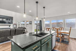 Kitchen with green cabinets, dark wood-style flooring, an island with sink, and recessed lighting