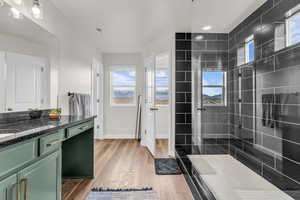 Bathroom with vanity, a tile shower, and light wood-style flooring