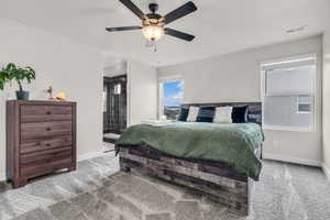 Carpeted bedroom featuring ensuite bath and ceiling fan