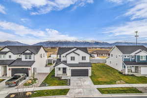 Modern farmhouse style home featuring a residential view, board and batten siding, a mountain view, concrete driveway, and stone siding