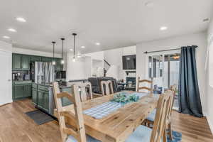 Dining area with light wood finished floors, stairs, recessed lighting, and a fireplace