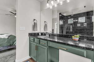 Bathroom with vanity, tiled shower, and wood finished floors