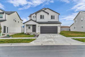 View of front of home featuring stone siding, board and batten siding, concrete driveway, and a garage