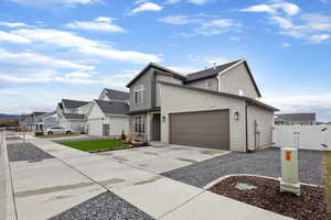 View of front of home with a gate, concrete driveway, a garage, and a residential view