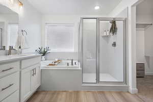 Full bath with vanity, a shower stall, a garden tub, and light wood-type flooring