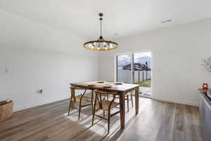 Dining space with wood finished floors and a chandelier