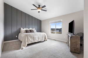 Bedroom featuring a decorative wall, carpet flooring, a ceiling fan, and an accent wall