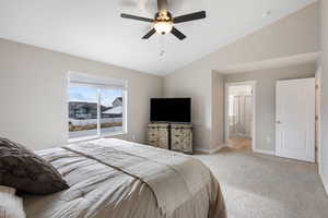 Carpeted bedroom with lofted ceiling, a ceiling fan, and ensuite bathroom