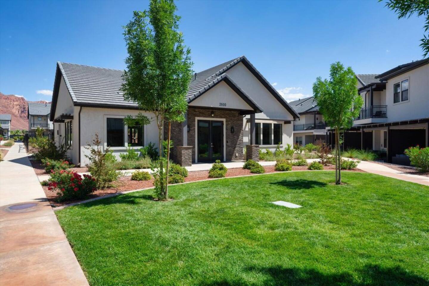 CLUB HOUSE: View of front facade featuring a front yard, stucco siding, brick siding, and a tile roof