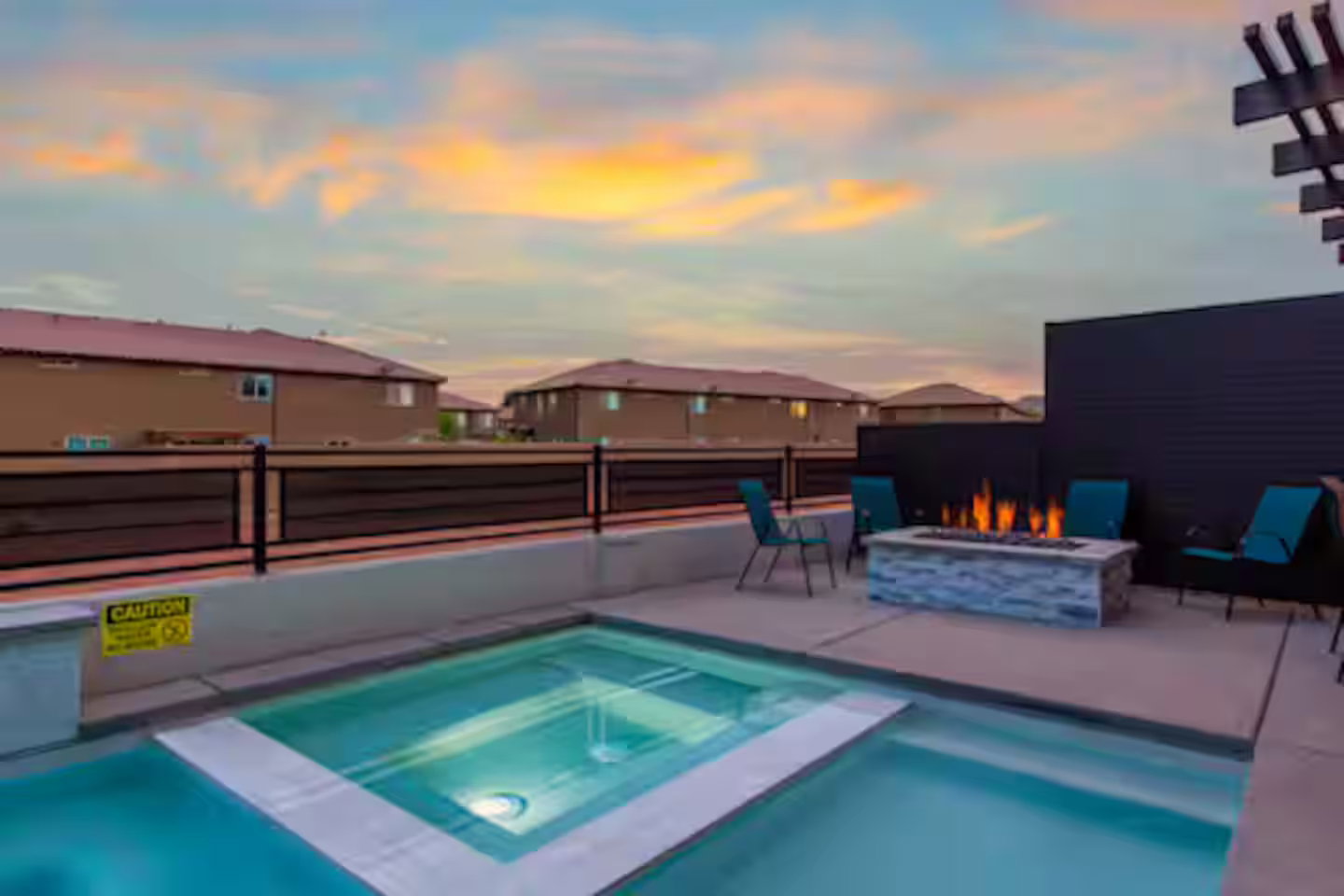 View of pool featuring an outdoor fire pit, a pool with connected hot tub, and a residential view