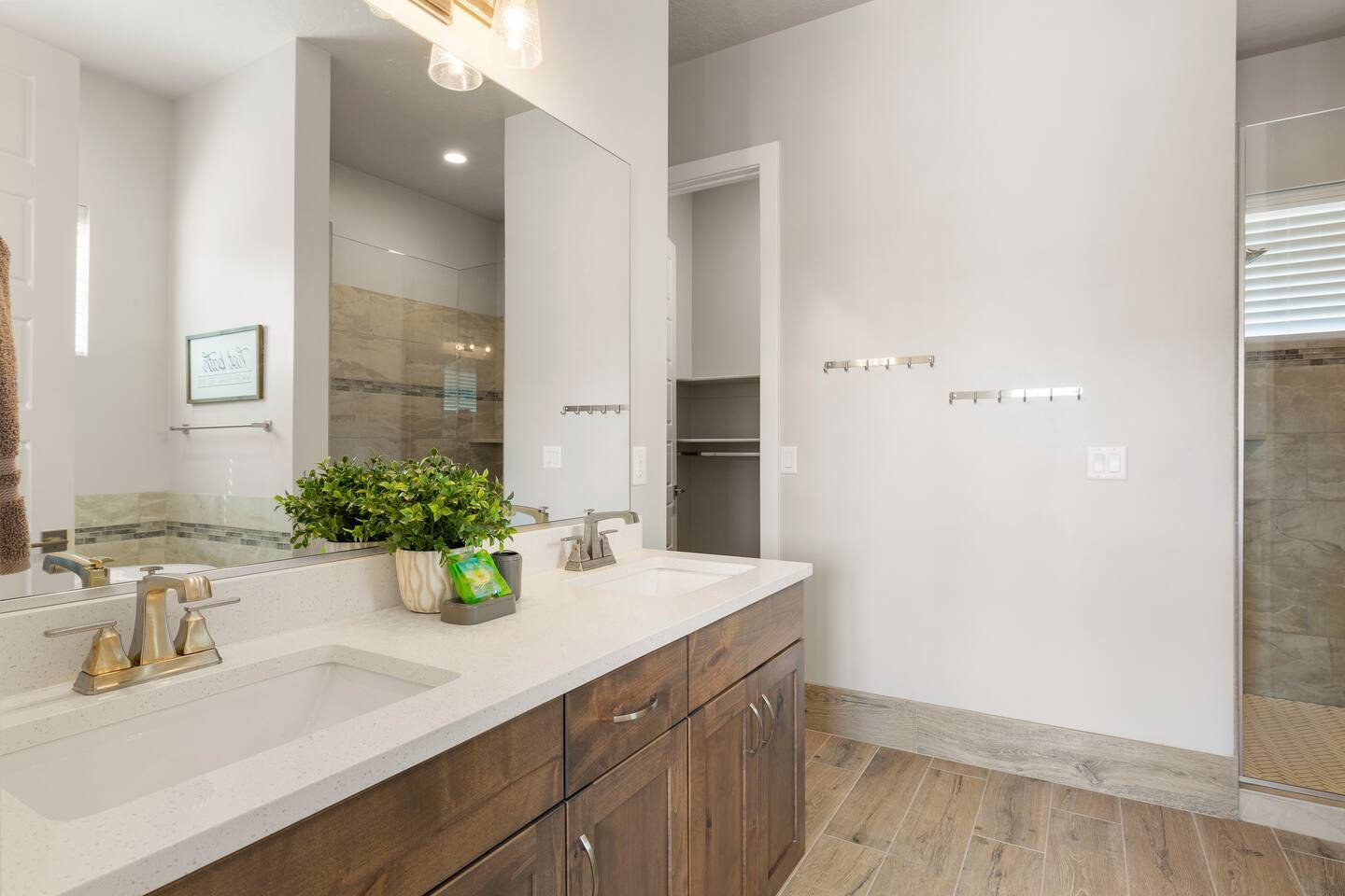 Bathroom with double vanity, light wood finished floors, and a shower stall